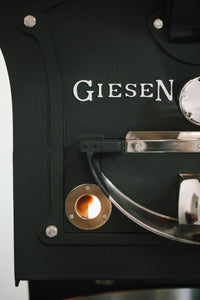 A close up of the coffee roaster, displaying the 'Geisen' brandmark